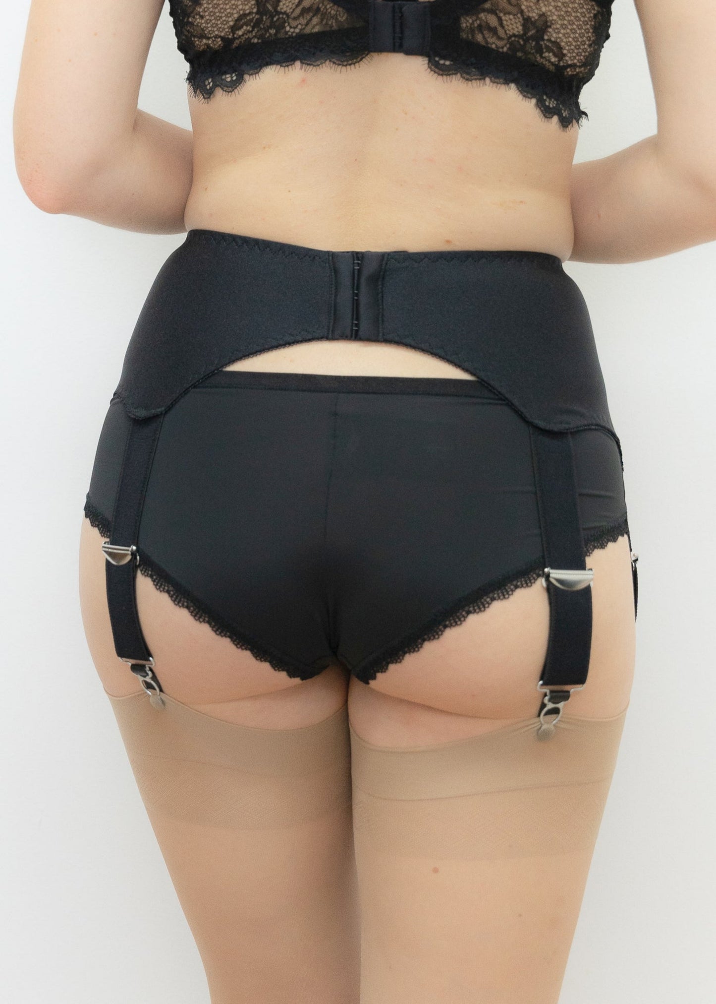 A black wide Iris garter belt with a deep V-style design, featuring six extra wide adjustable straps, back view