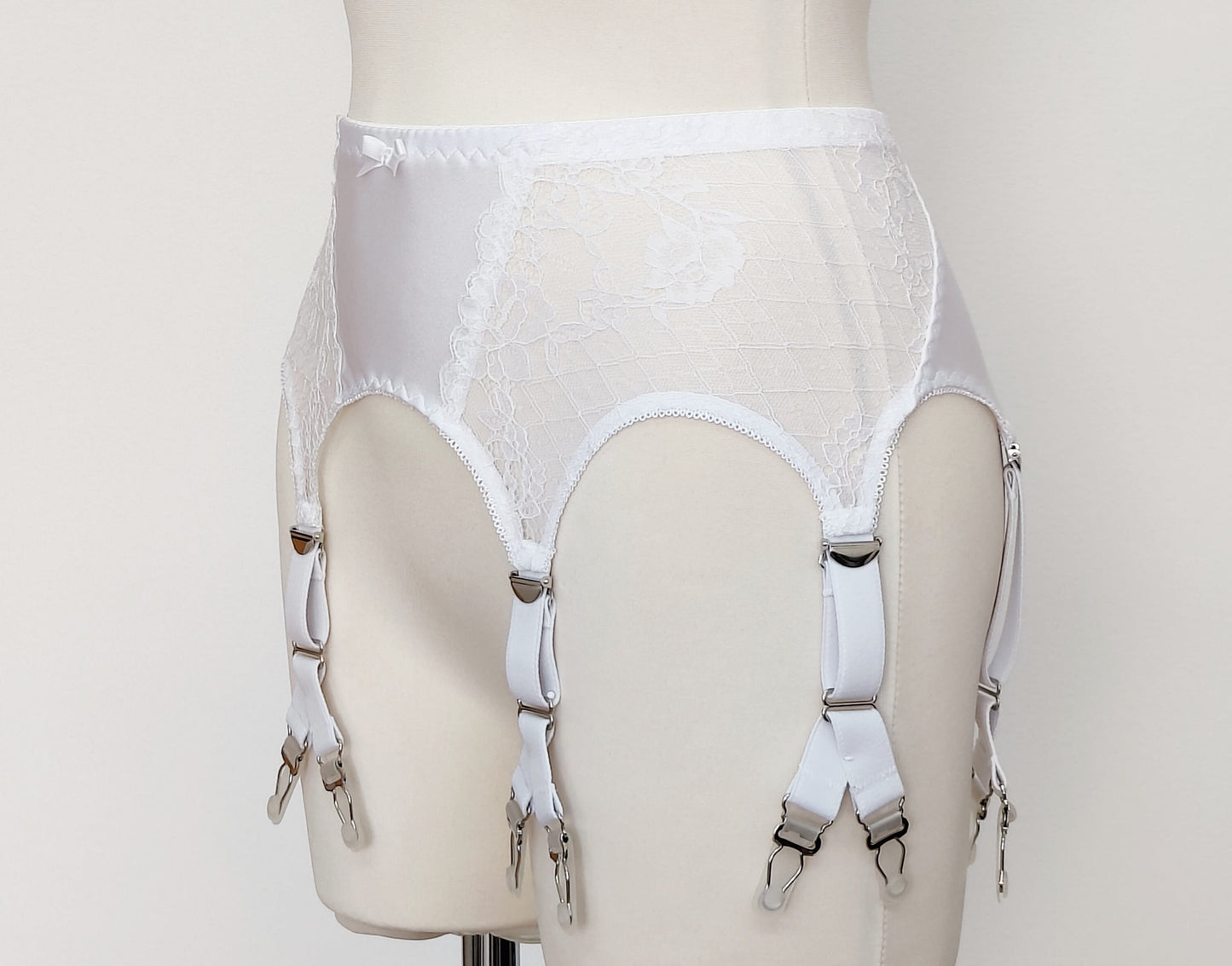 A white lace Rita garter belt with 6 Y-straps and a bow detail, displayed on a mannequin, side view