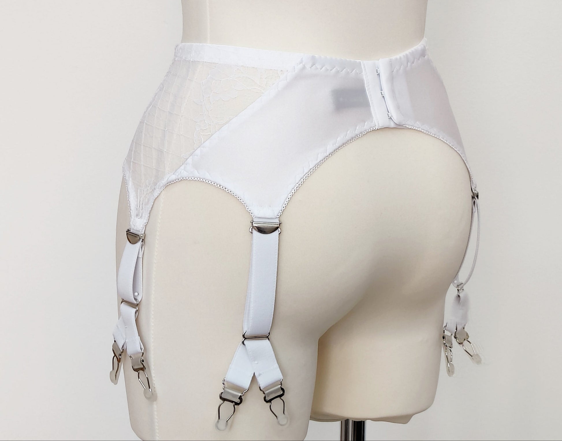 A white lace Rita garter belt with 6 Y-straps and a bow detail, displayed on a mannequin, back view