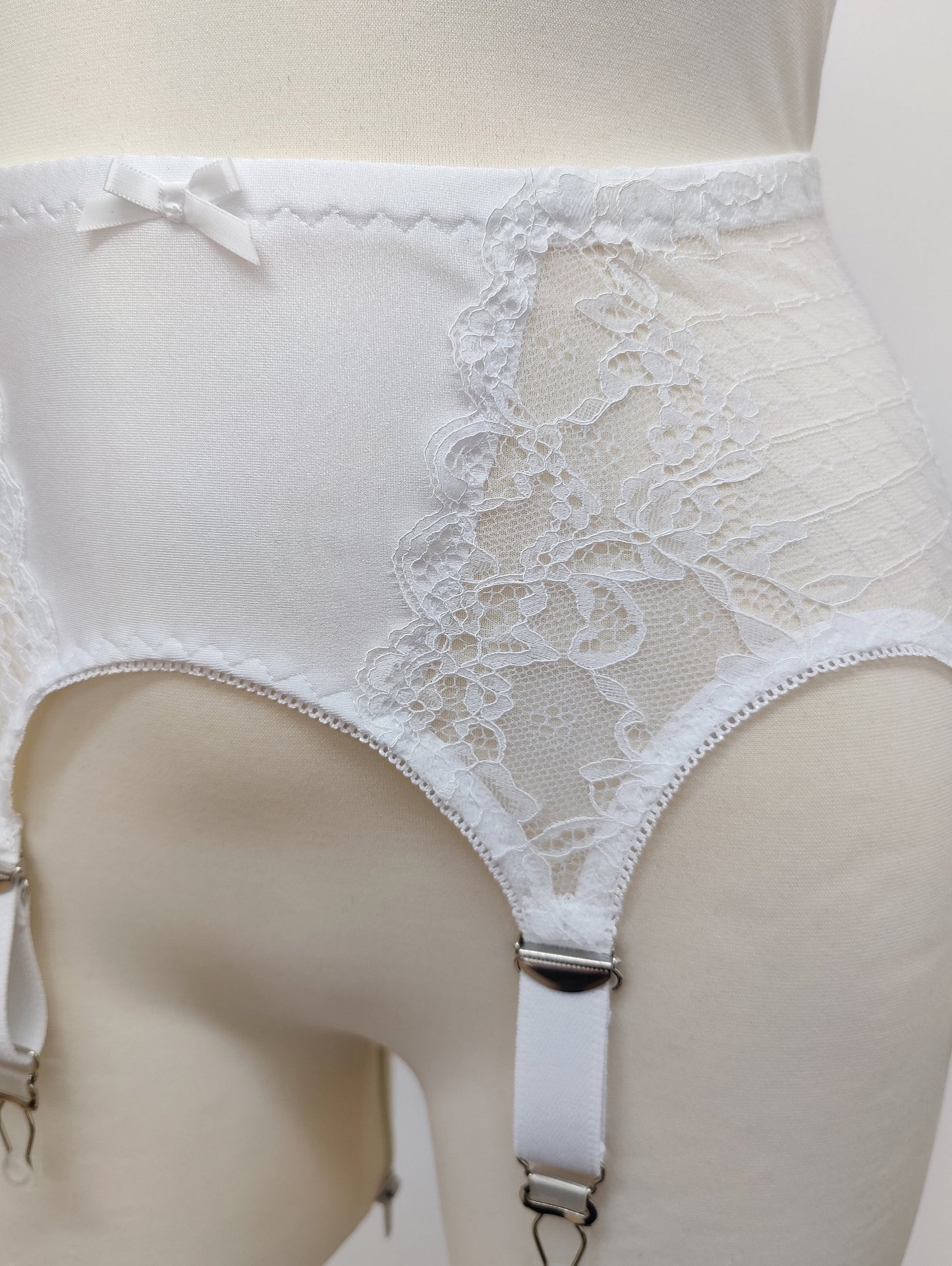 A white lace Mona garter belt with 6 adjustable straps and hook and eye closure, detail