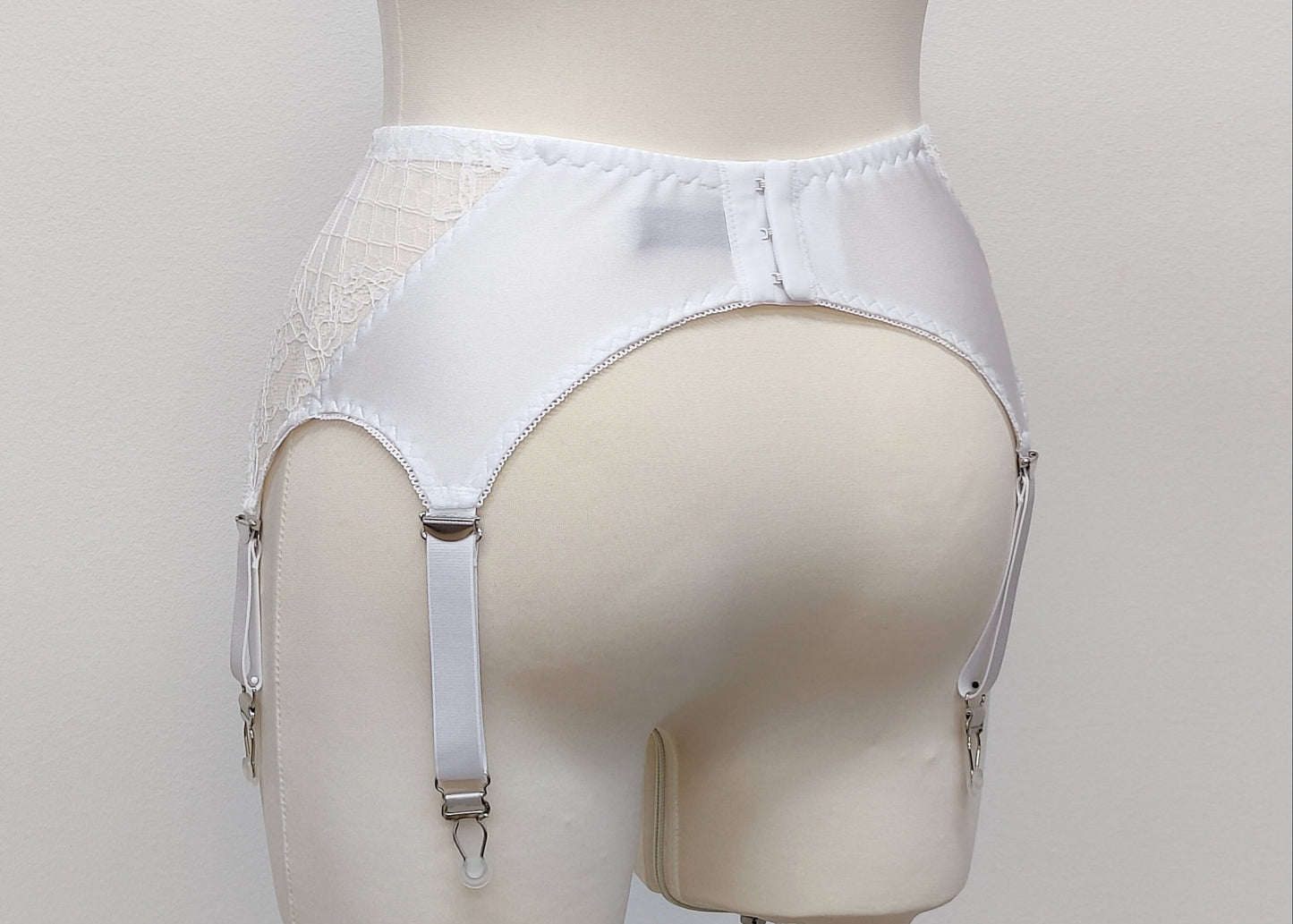 A white lace Mona garter belt with 6 adjustable straps and hook and eye closure, back view