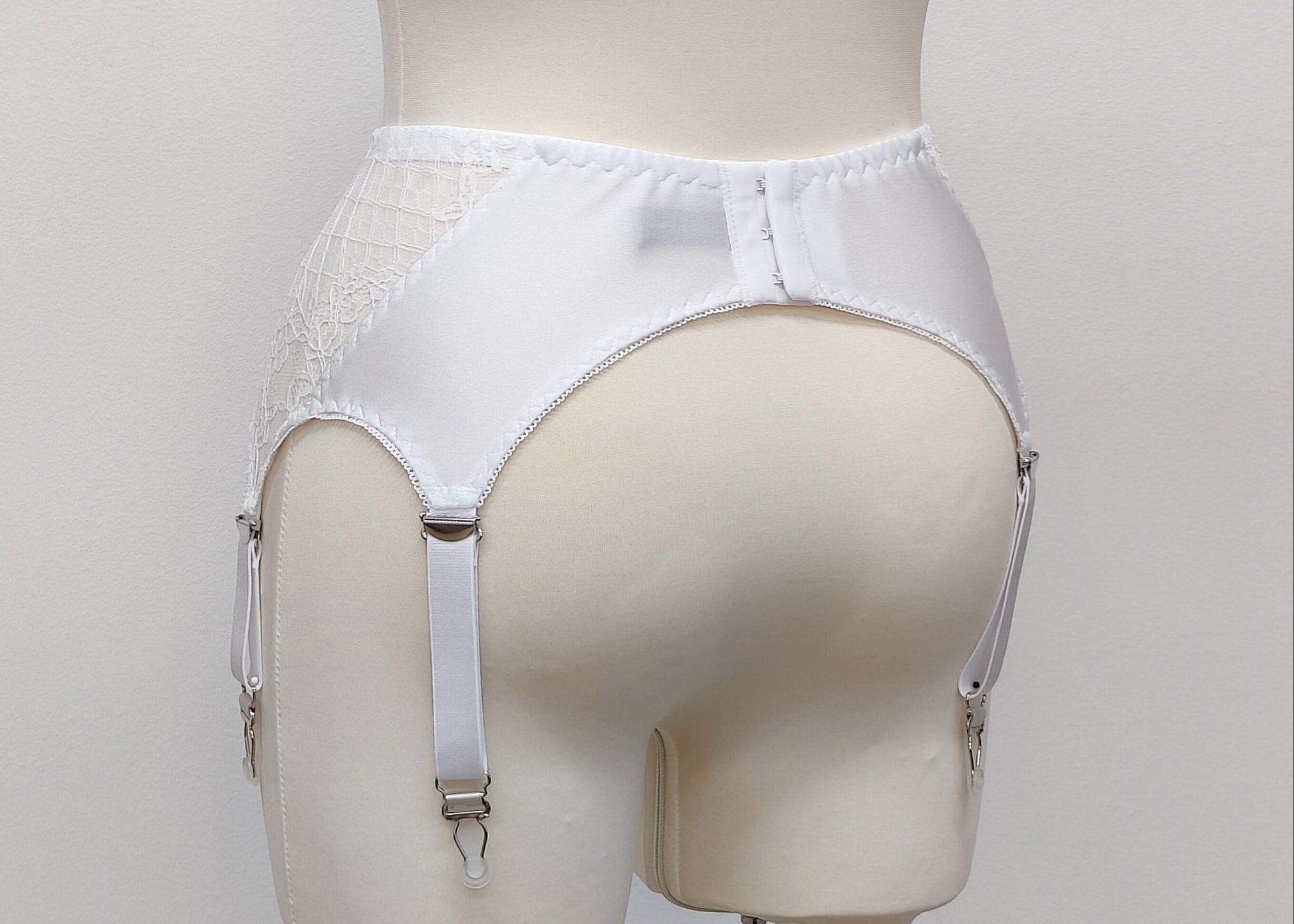 A white lace Mona garter belt with 6 adjustable straps and hook and eye closure, back view