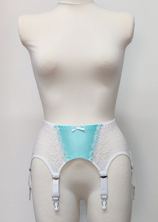 A white lace and Aqua blue Lycra, Mona garter belt with 6 adjustable straps and hook and eye closure, displayed on a mannequin.