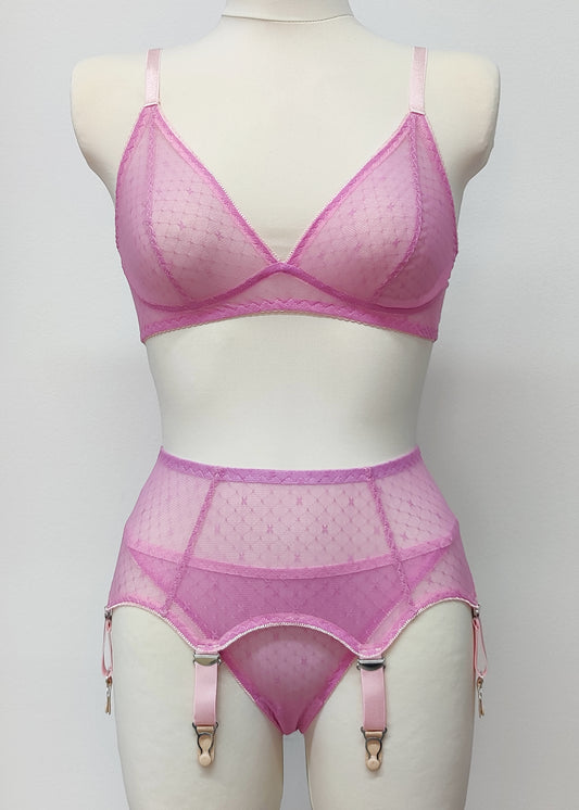 A pink sheer LULA garter belt with 6 adjustable straps displayed on a mannequin. The belt has a transparent mesh design with pink accents and metal hardware.