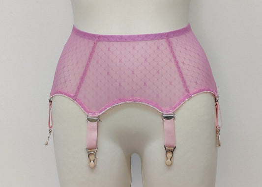 A pink sheer LULA garter belt with adjustable straps displayed on a mannequin. The belt has a transparent mesh design with pink accents and metal hardware.