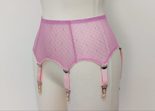 A pink sheer LULA garter belt with adjustable straps displayed on a mannequin. The belt has a transparent mesh design with pink accents and metal hardware. side view