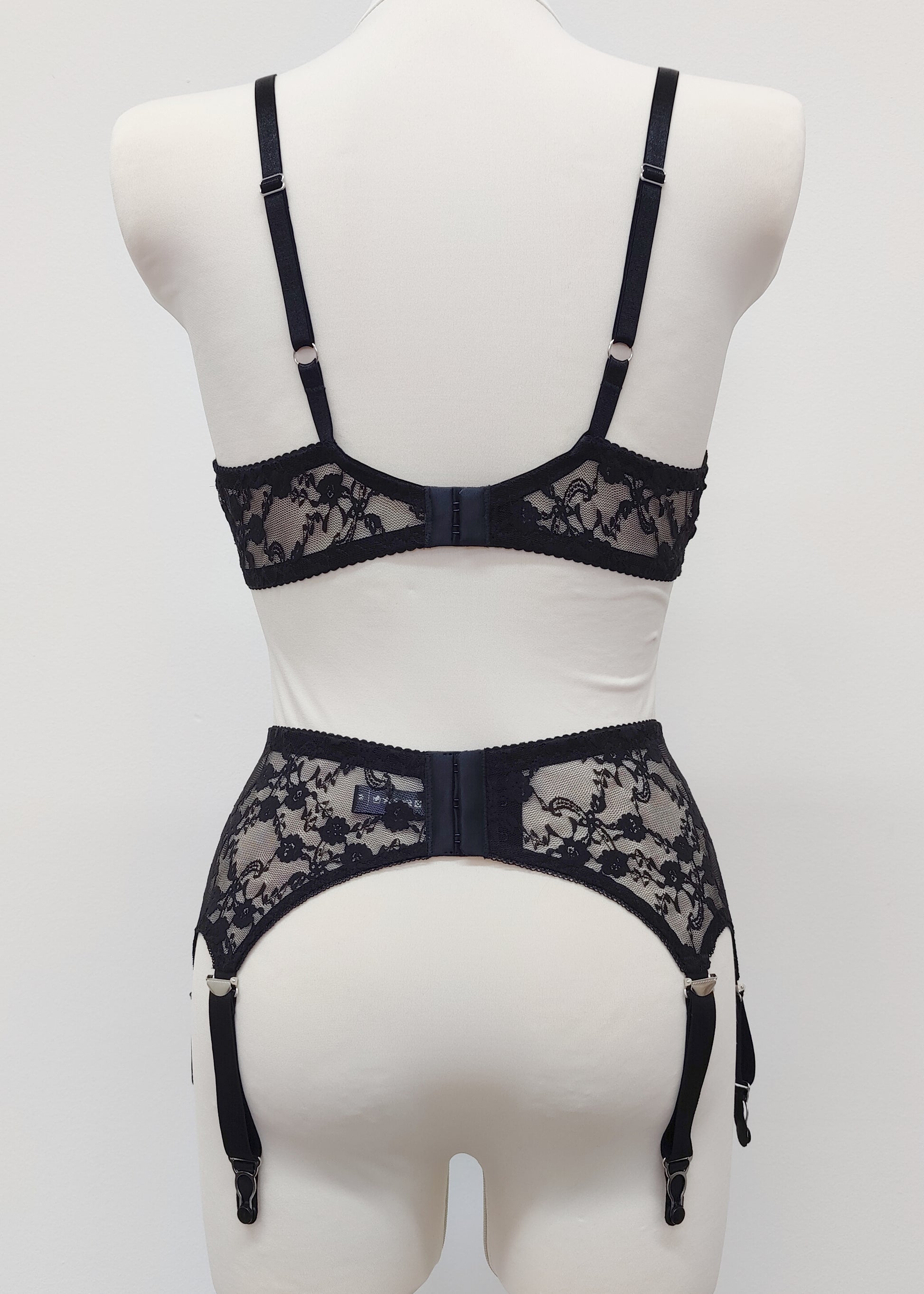 Claire is a black lace garter belt with 4-8 adjustable straps, displayed on a mannequin with matching wireless Chloe bralette, back view