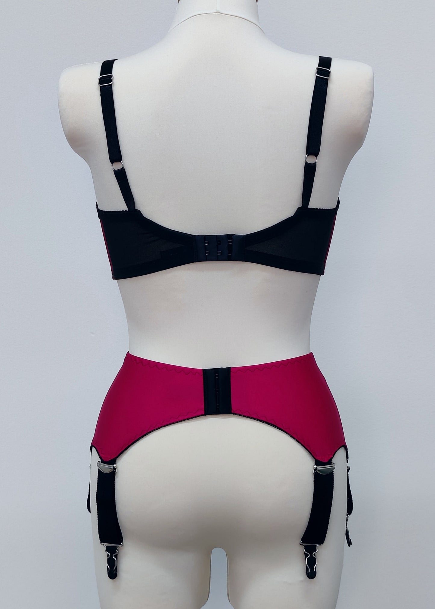 magenta pink wide vintage style Iris garter belt, with black trim and 6 extra wide black straps, here shown with matching Audrey full cup bra, back view