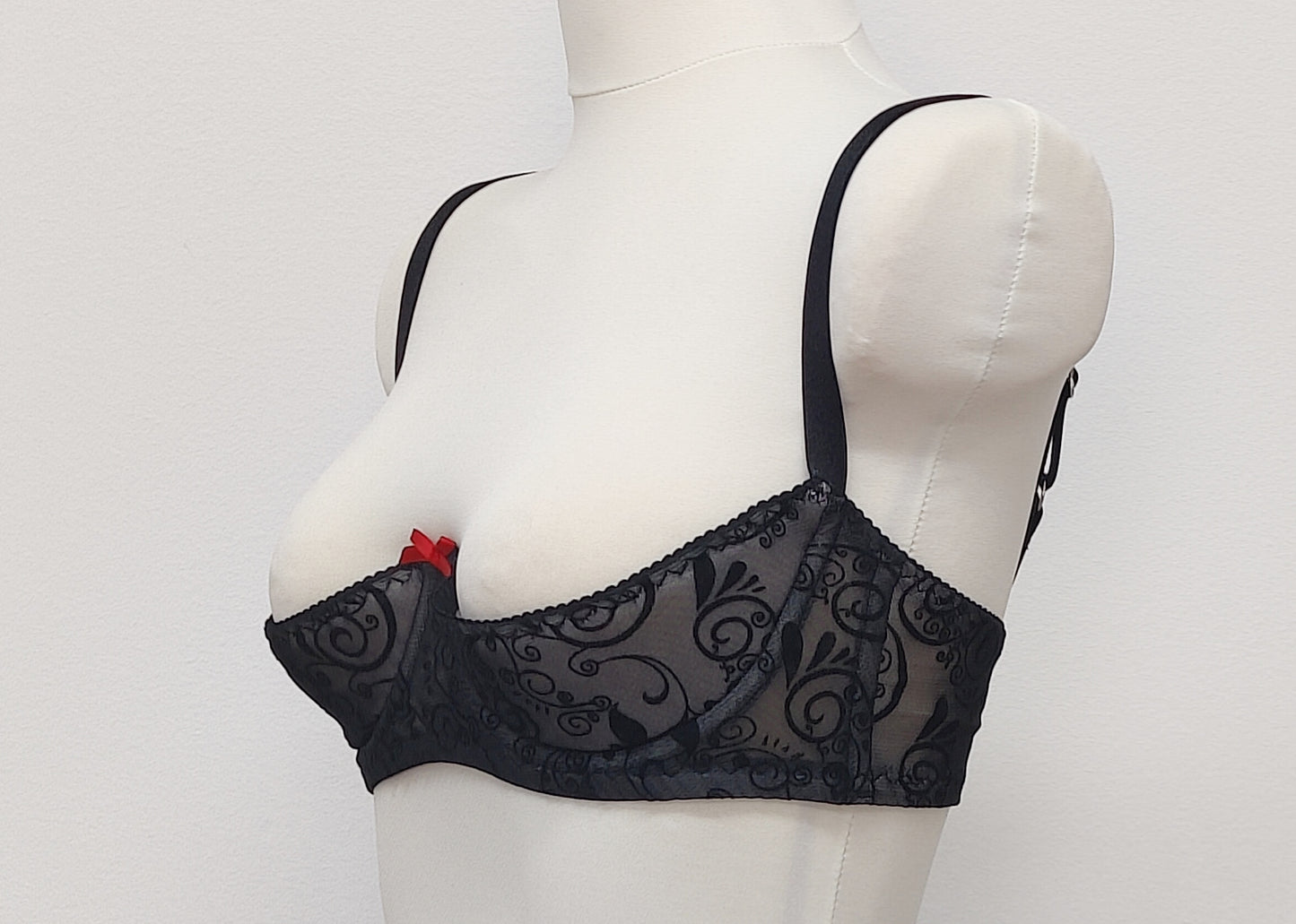 black swirl patterned mesh, quarter cup bra with red bow, side look