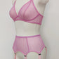 Pink sheer LULA garter belt with 6 adjustable straps displayed on a mannequin. The belt has a transparent mesh design with pink accents and metal hardware. side view