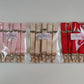 Three packages of suspenders in pink, beige, and red, each containing six straps with beige grips, sealed in clear plastic bags with white brand labels.