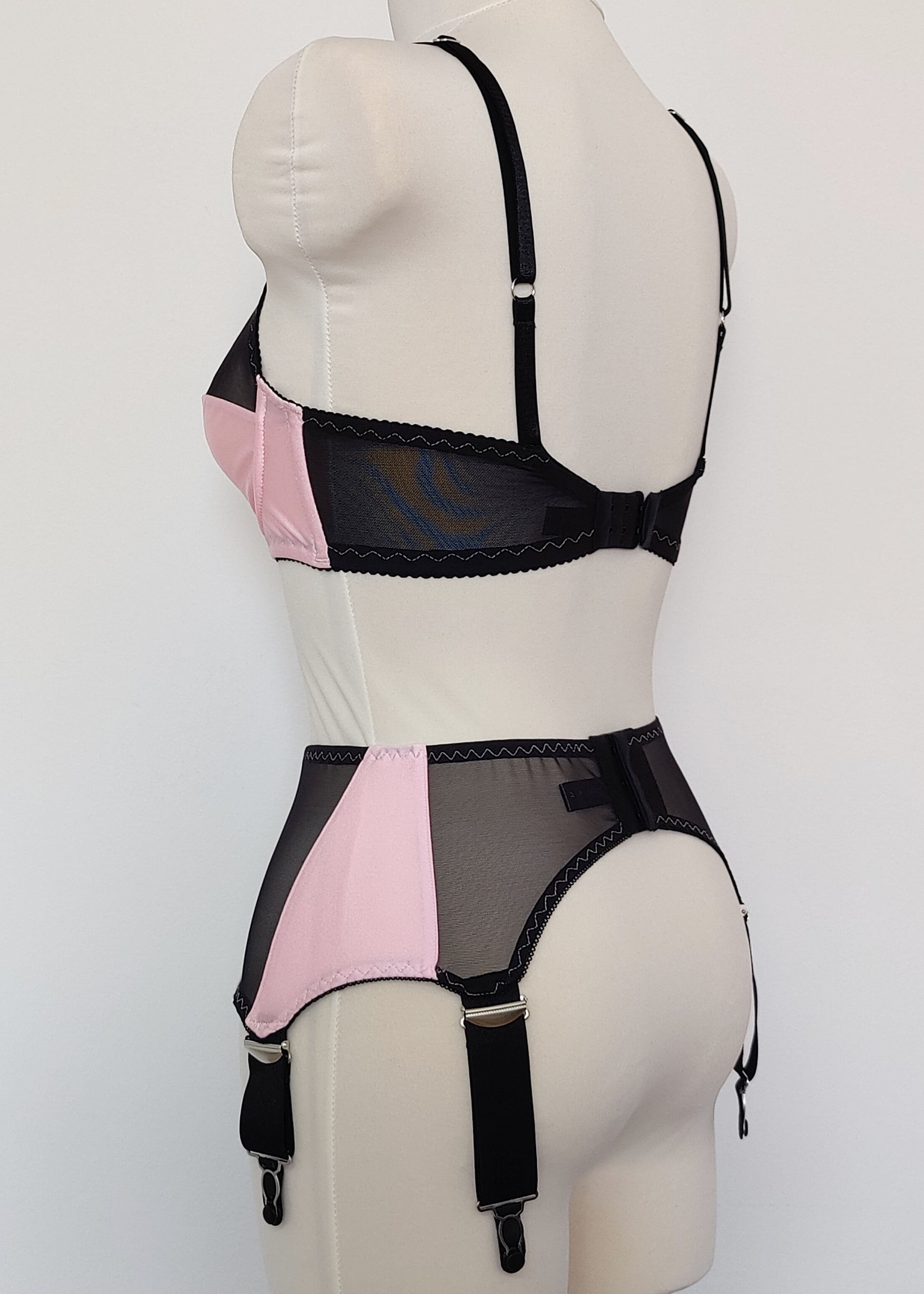 pink Audrey bra with black sheer upper part of the cup, with matching Iris garter belt, back view