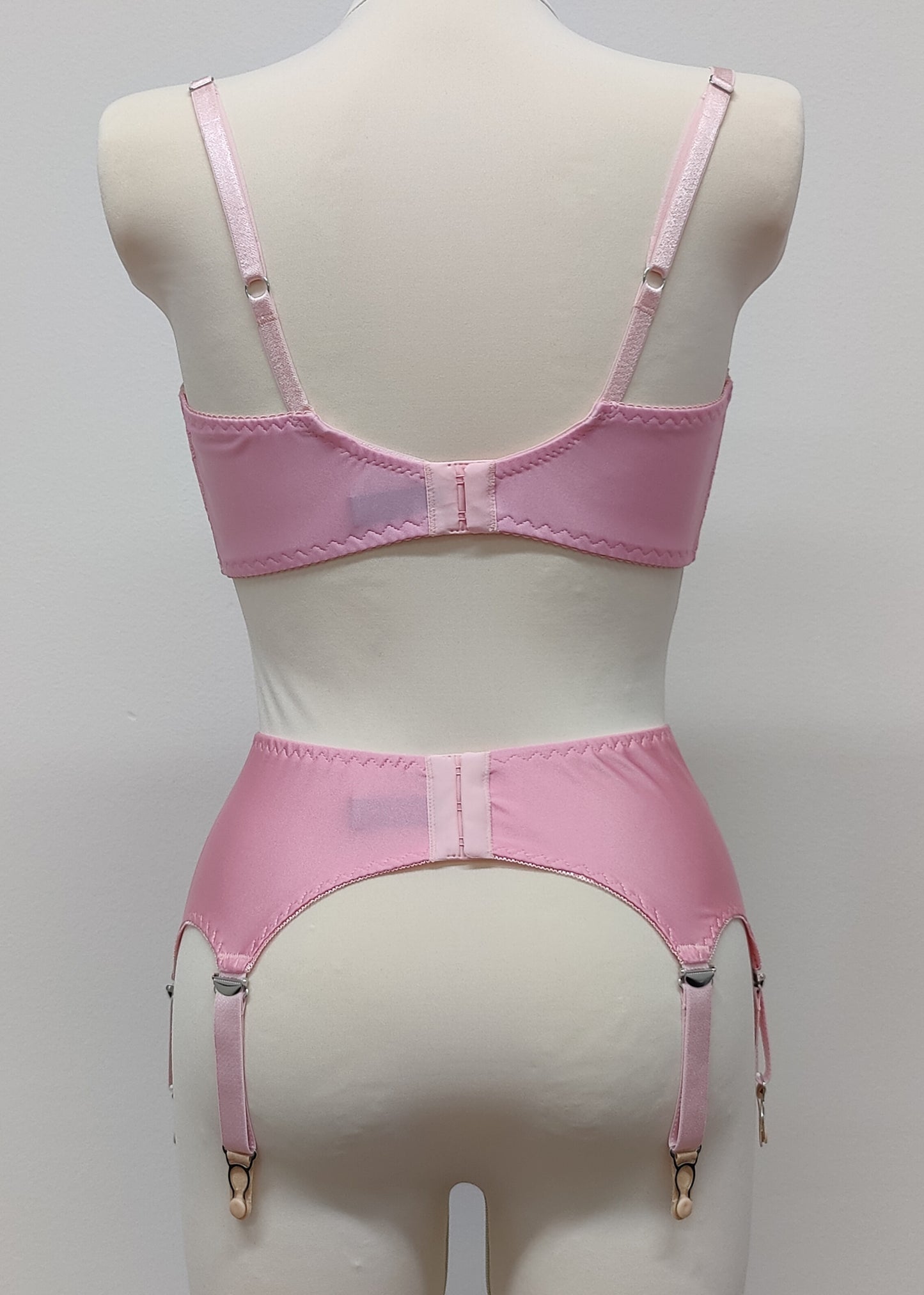 Pink narrow Nina garter belt, 60's style with 6 adjustable straps and hook and eye closure at the back. Shown with matching  bra. back view