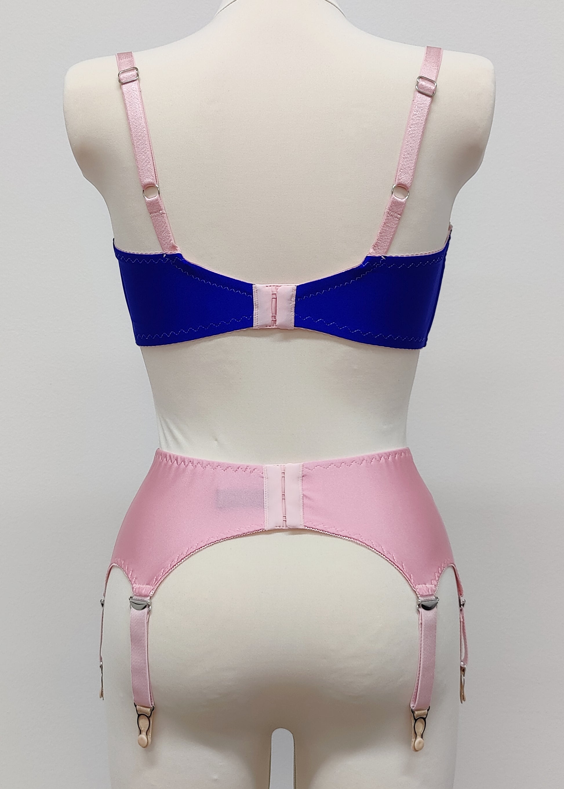 Quarter cup Lucy bra, here shown in blue with pink lace, straps and trims. On the photo is also Nina 6 strap garter belt in pink. Back view