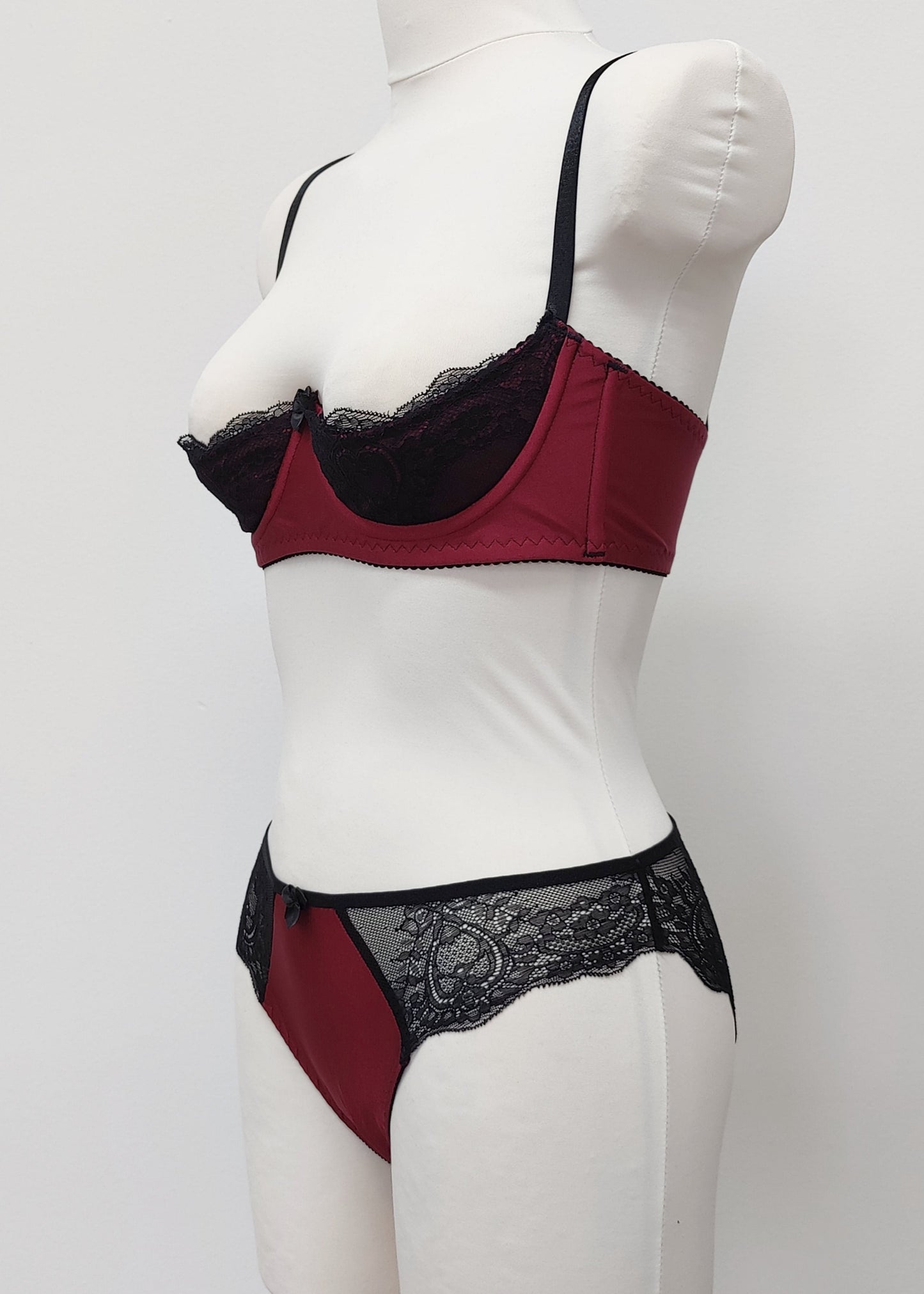 Maroon Red and black lace lingerie set on a mannequin against a white background. Zigi tanga with lace on the back and side panels and Lucy quarter cup bra, side view