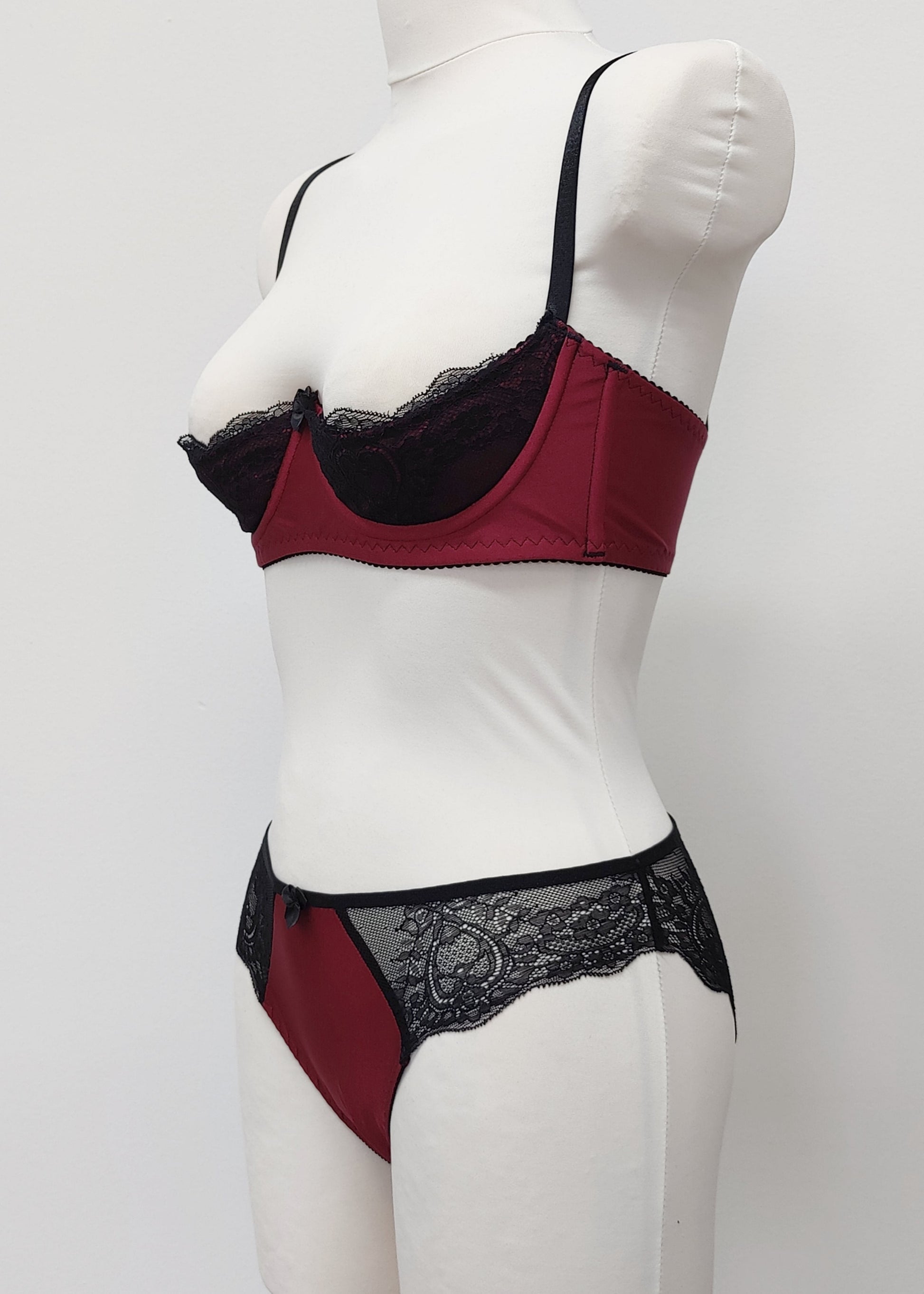 Maroon Red and black lace lingerie set on a mannequin against a white background. Zigi tanga with lace on the back and side panels and Lucy quarter cup bra, side view