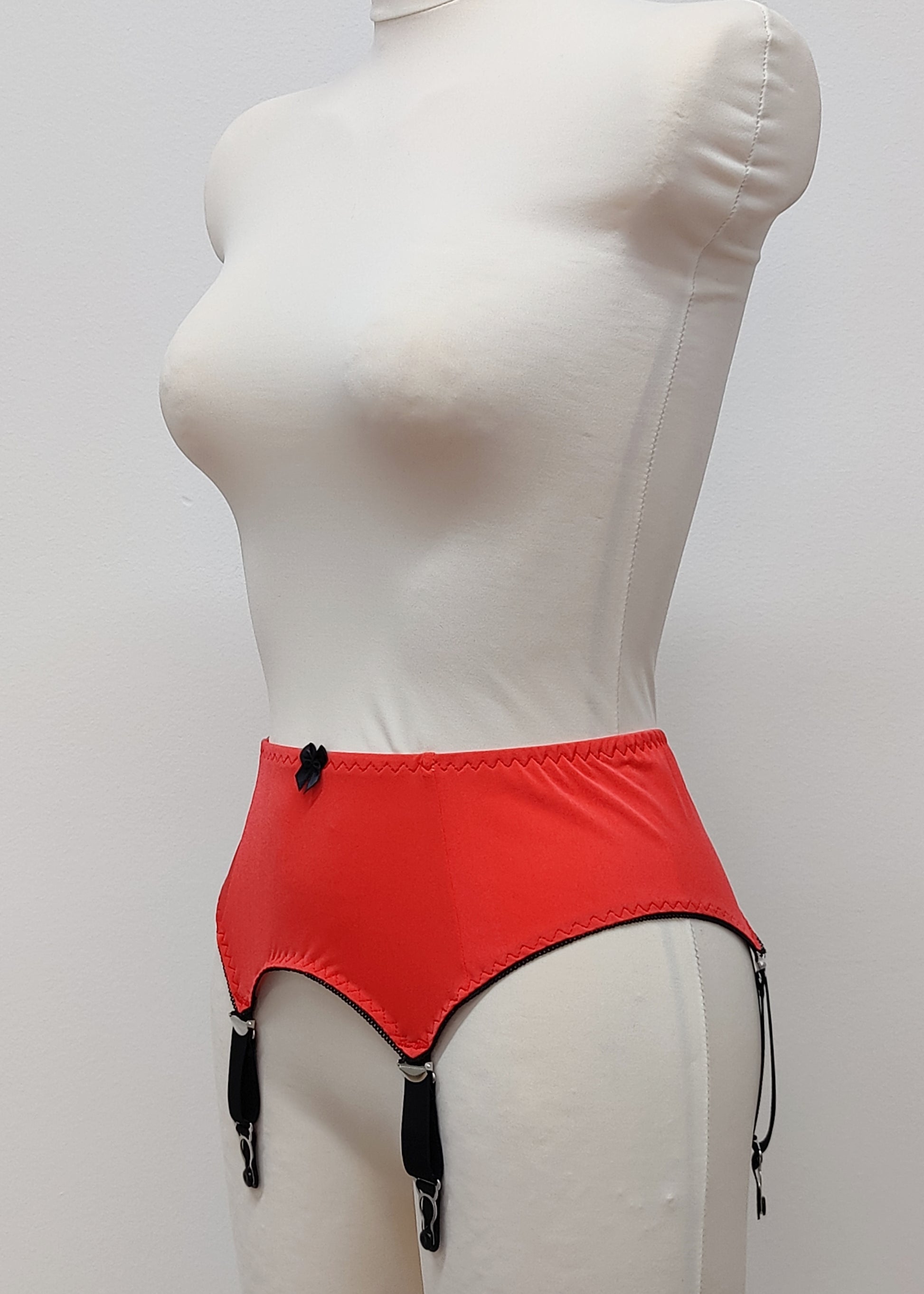 Sunset colour, 4 strap Greta garter belt with black straps on a mannequin against a white background, side view
