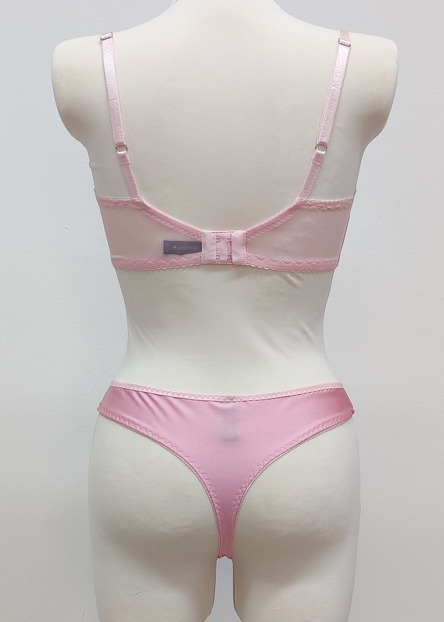 Mannequin wearing a  pink Gina quarter cup bra and Mia thong with sheer pink side panels, back view