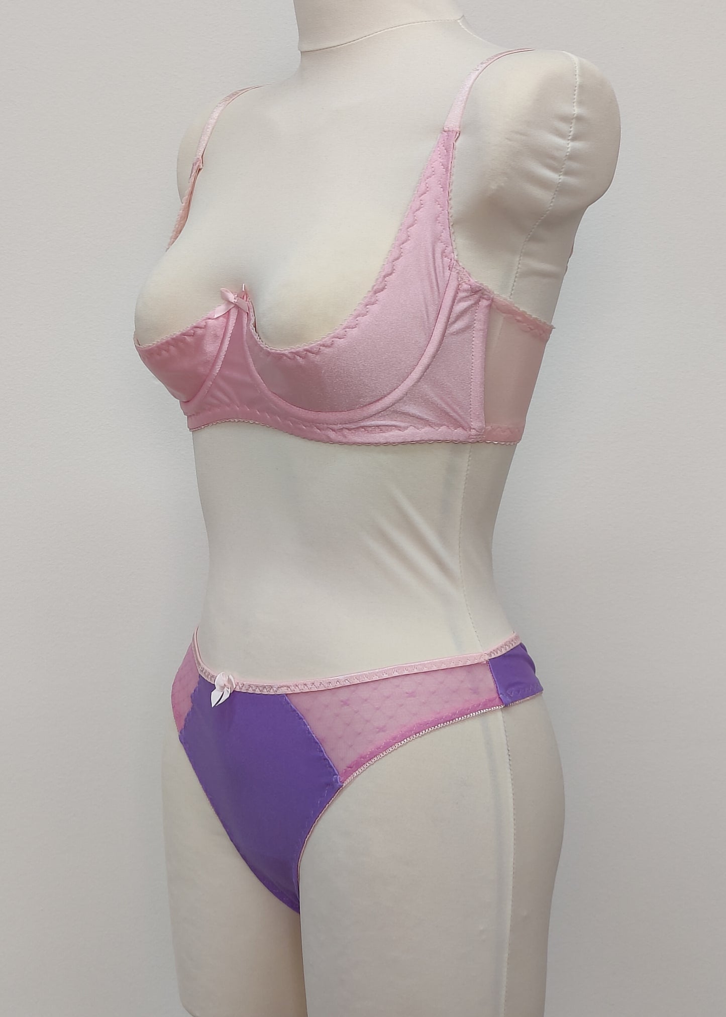 Mannequin wearing a  pink Gina quarter cup bra and  purple Mia thong with sheer pink side panels, side view 