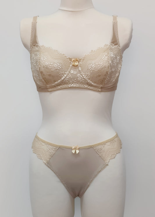 Beige lingerie set on a mannequin against a plain background. Zigi thong with side lace panels and Alice bra