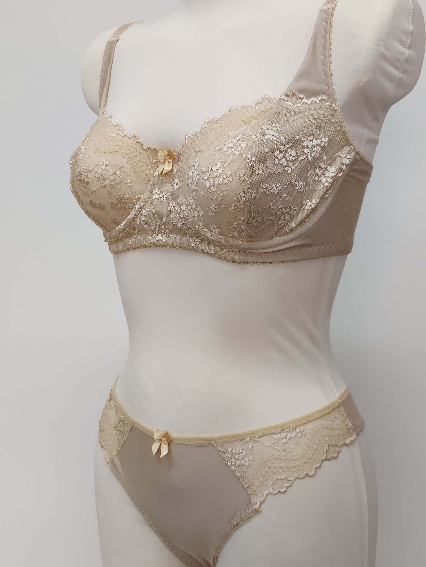 Beige lingerie set on a mannequin against a plain background. Zigi thong with side lace panels and Alice bra, side view