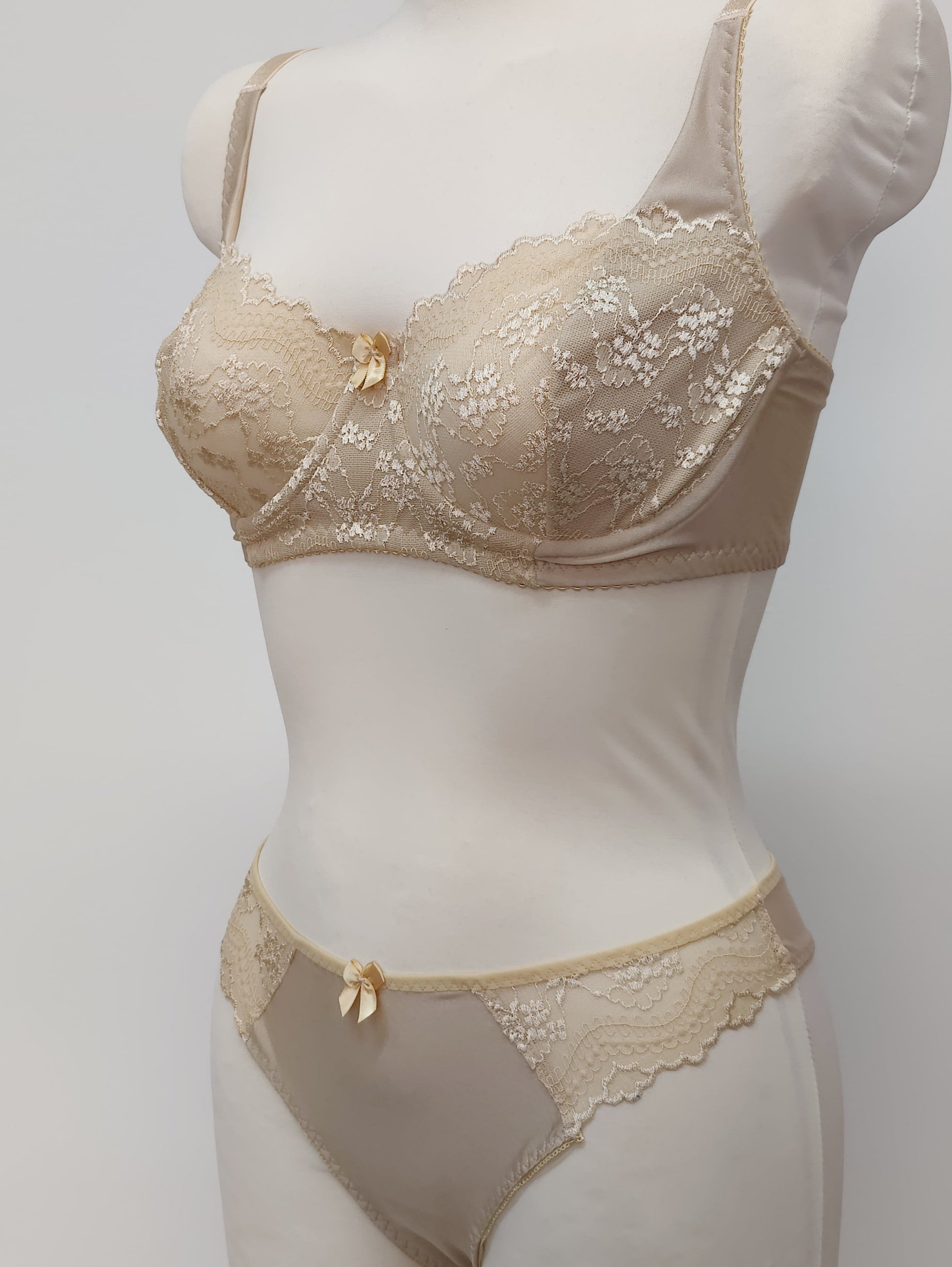 Beige lingerie set on a mannequin against a plain background. Zigi thong with side lace panels and Alice bra, side view