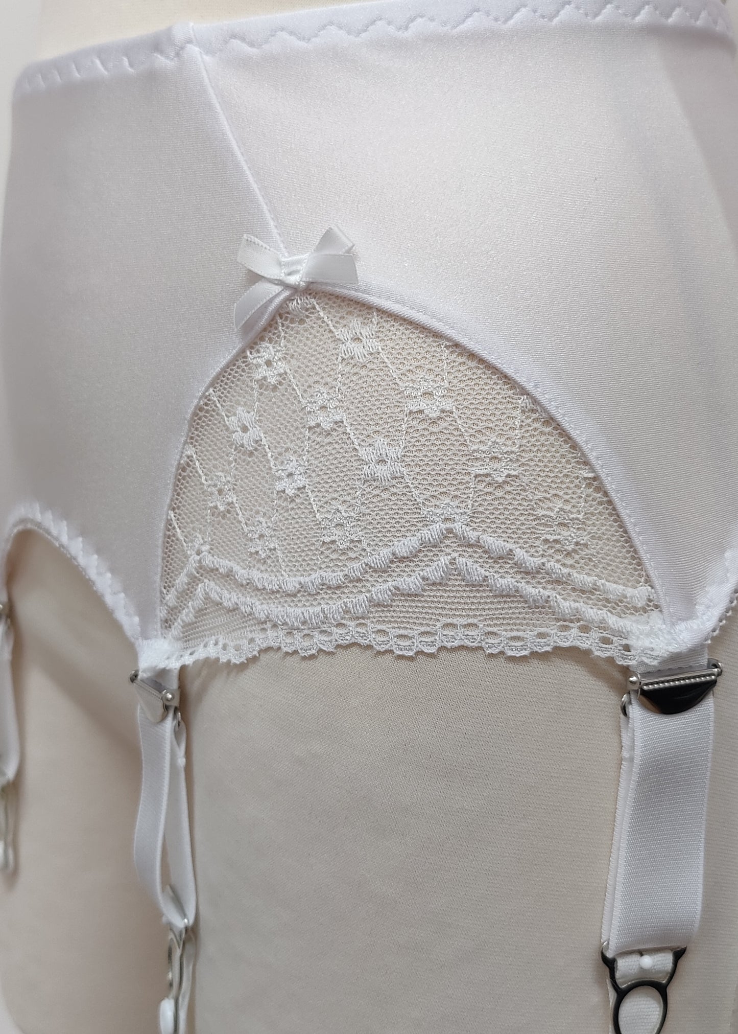 White lace garter belt on a mannequin against a neutral background, lace detail
