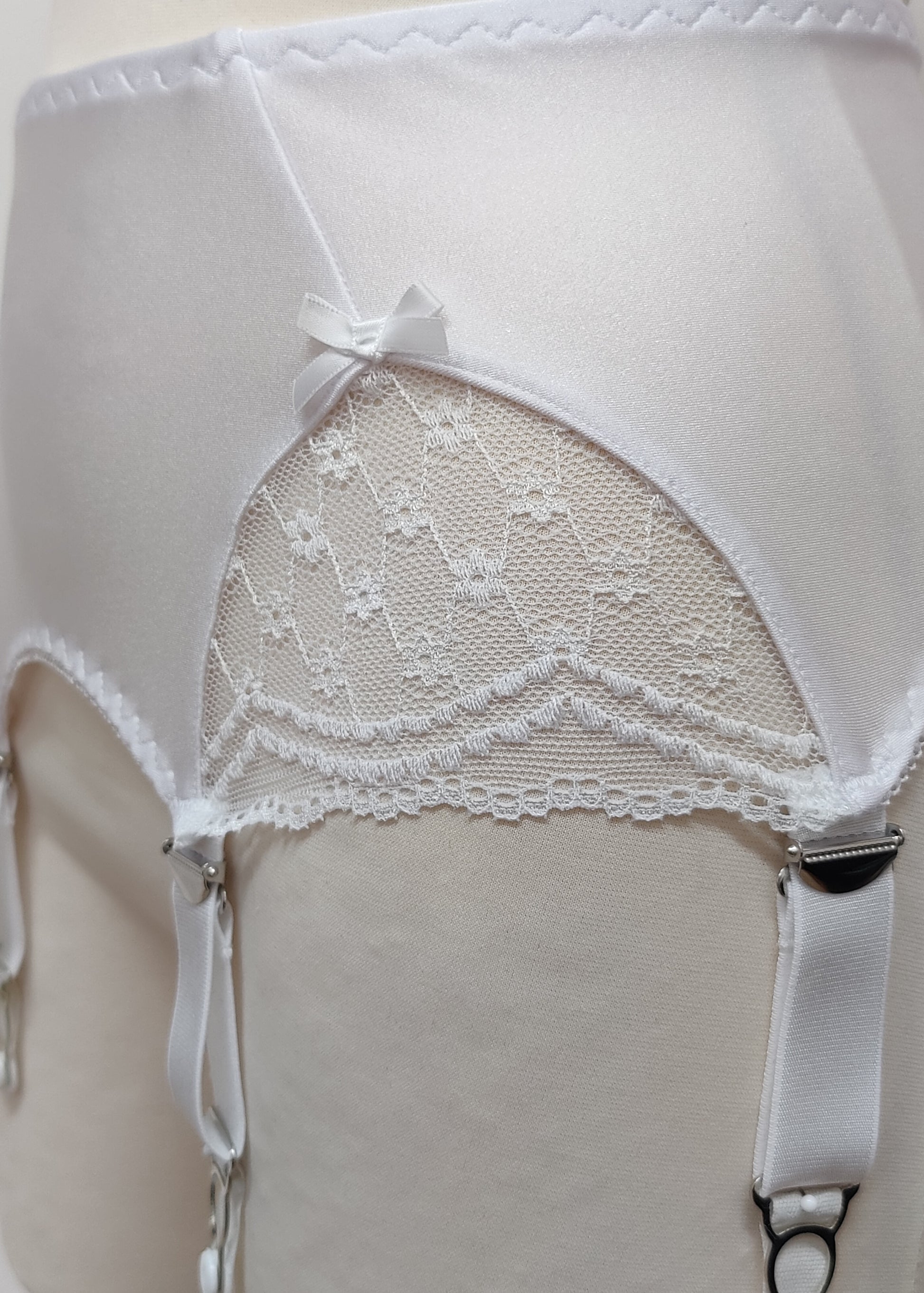 White lace garter belt on a mannequin against a neutral background, lace detail