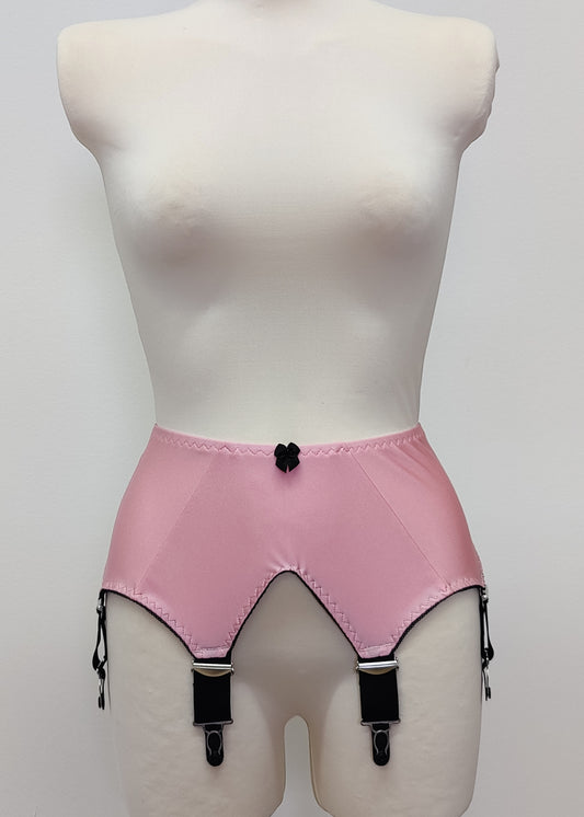 Pink high-waisted garter belt with black trim and black clips, displayed on a white mannequin torso against a light gray background.