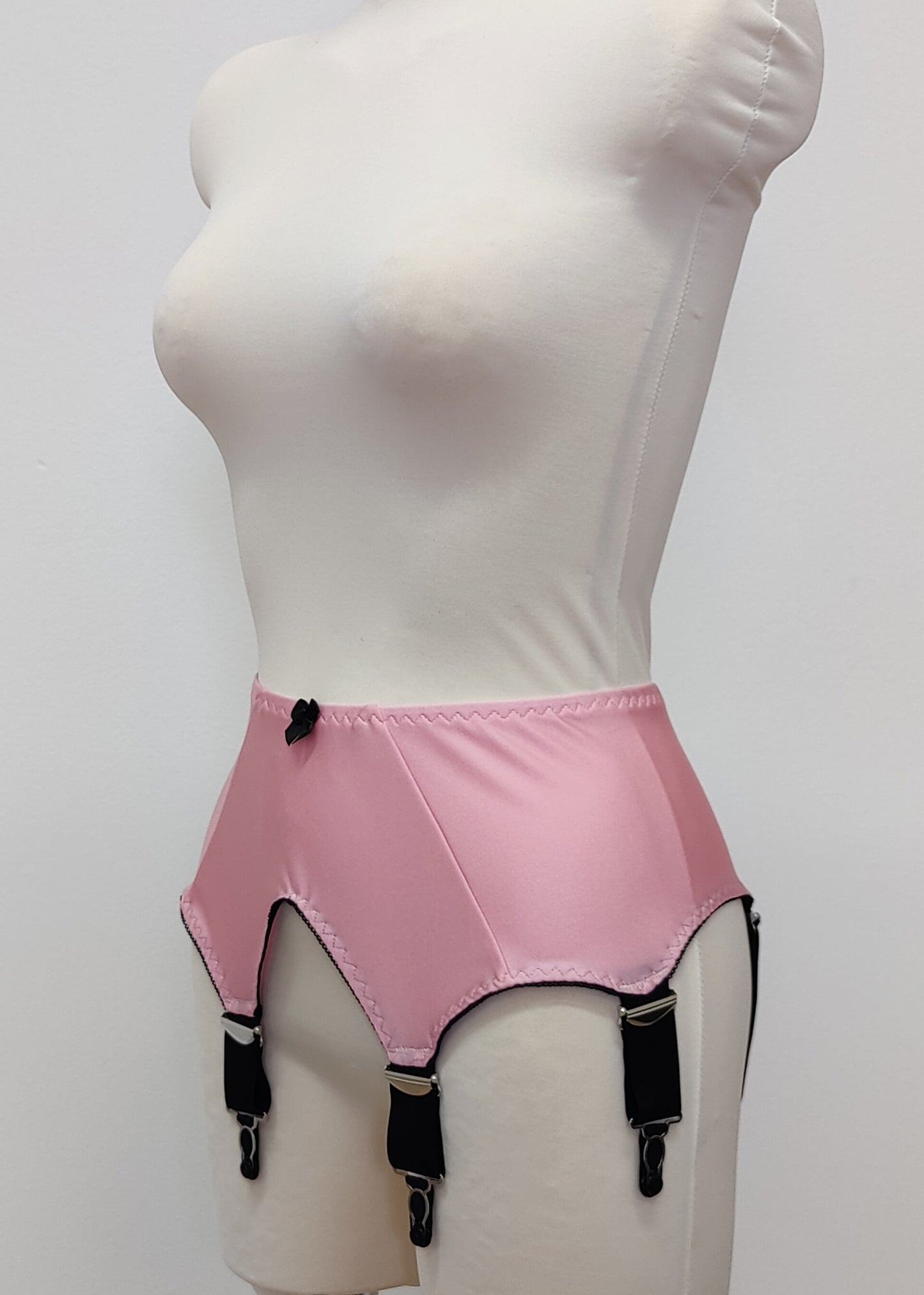Pink high-waisted garter belt with extra wide black straps and bows