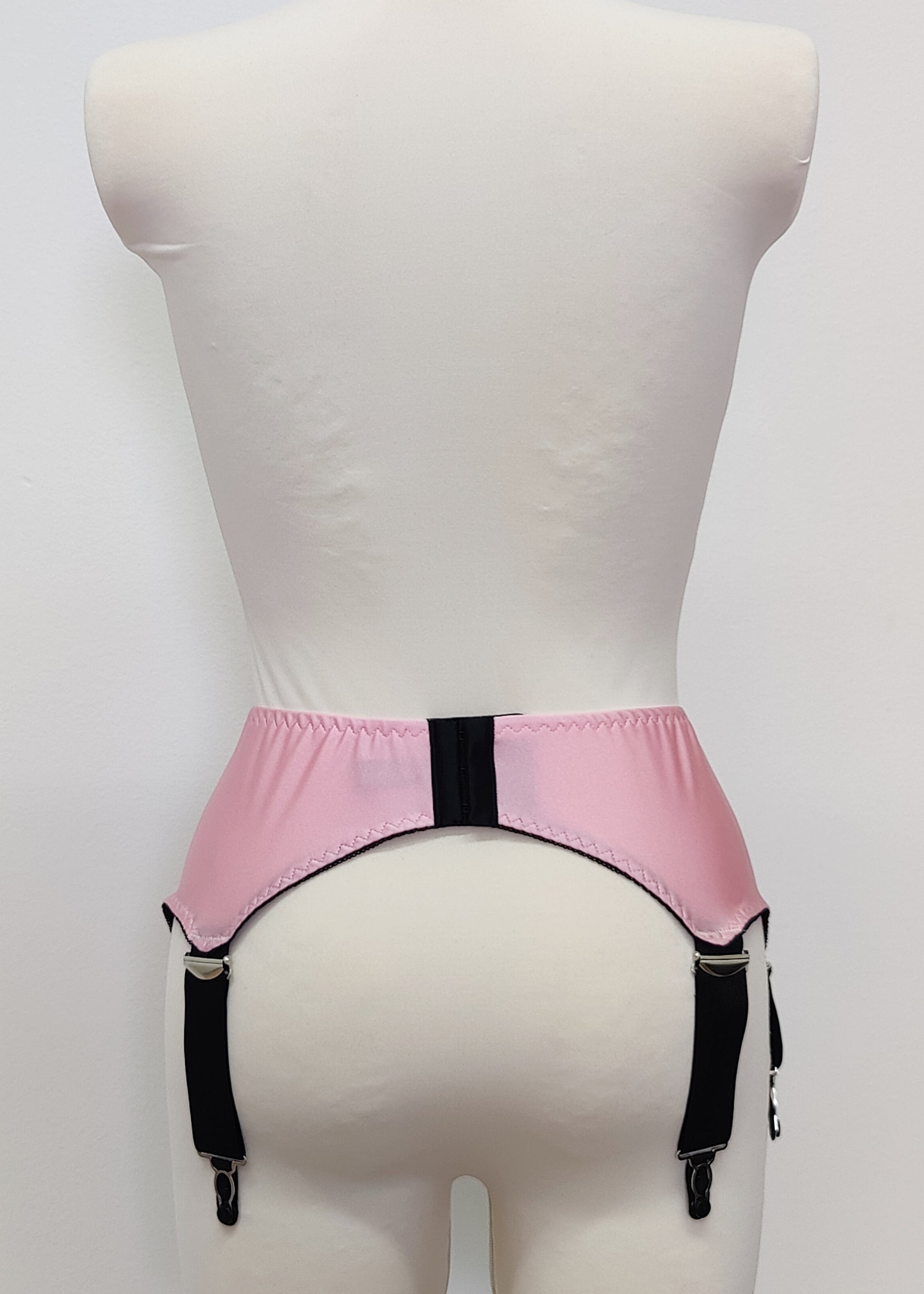 Pink high-waisted garter belt with extra wide black straps and bows